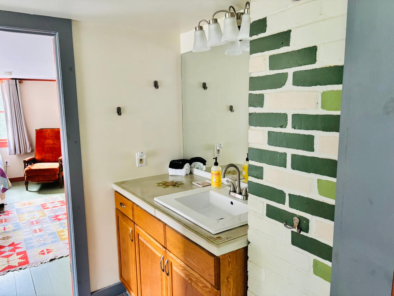 Vanity with green and white painted brick wall