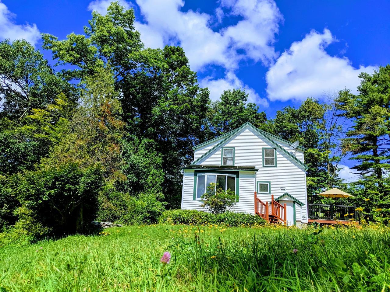 White farmhouse with chimney and large yard